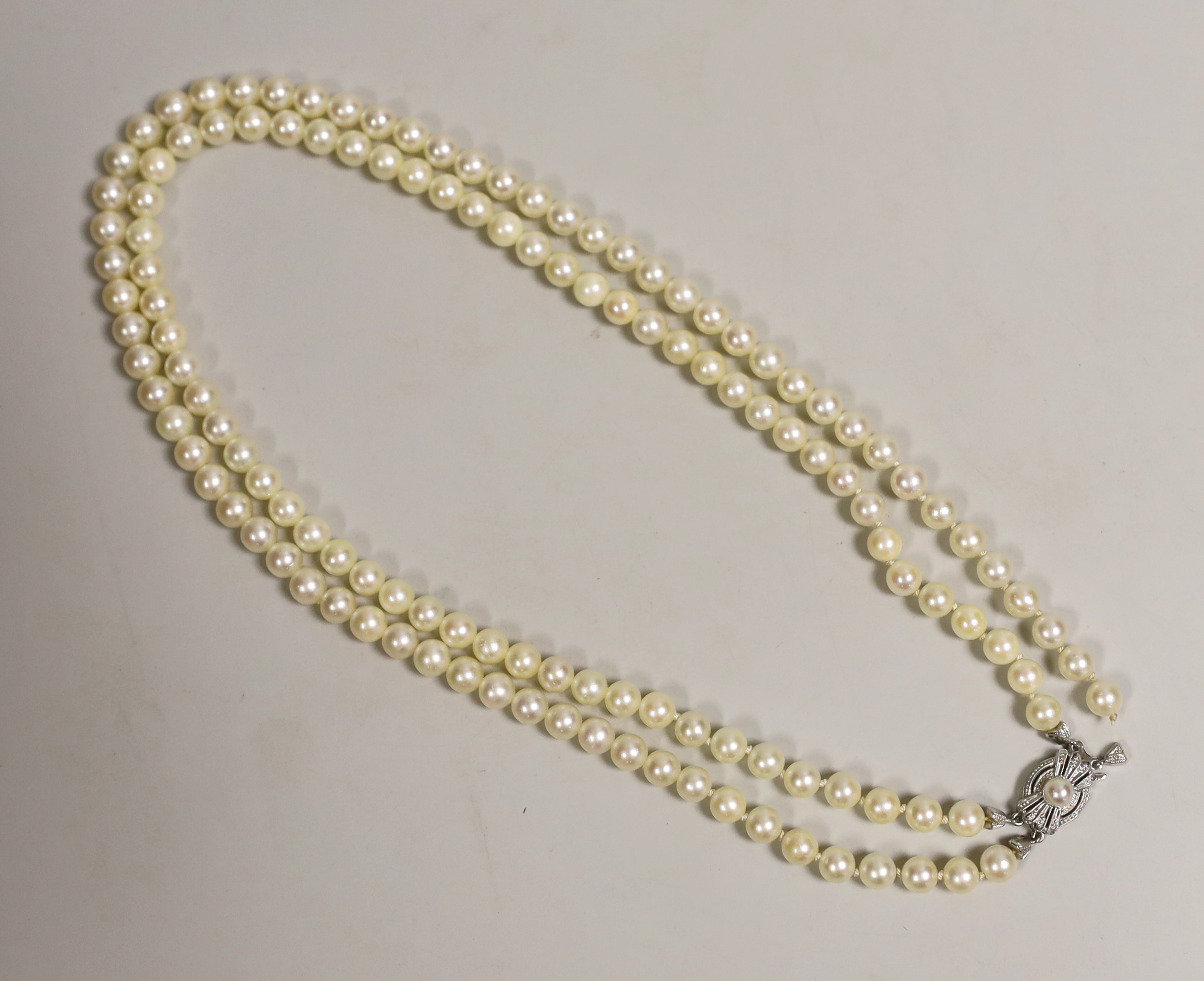 A mid to late 20th century double strand cultured pearl necklace, with cultured pearl set two colour 585 clasp, 43cm.